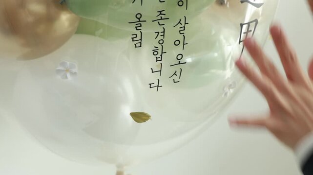 메시지가 적힌 풍선에 잎 장식을 하는 손
