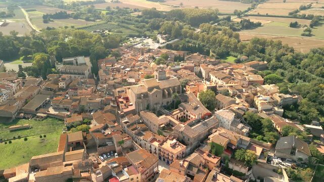 Aerial view of the historic town of Peralada with its medieval castle and stone rooftops surrounded by lush green fields in Peralada, Catalonia, Spain.