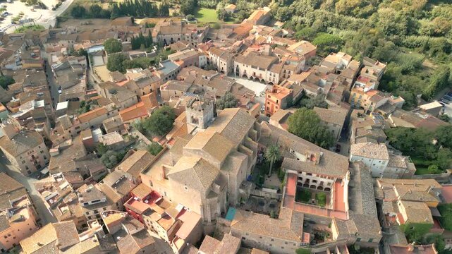 Aerial view of the historic town of Peralada with its stone buildings, terracotta rooftops, and the prominent church tower in the center of Peralada, Catalonia, Spain.