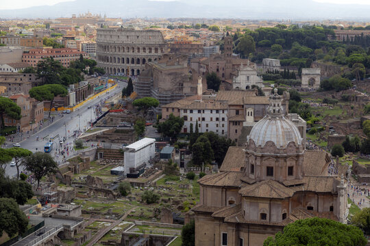 View of the Colosseum and the Roman Forum with historic ruins, stone structures, and surrounding urban landscape in Rome, Lazio, Italy.