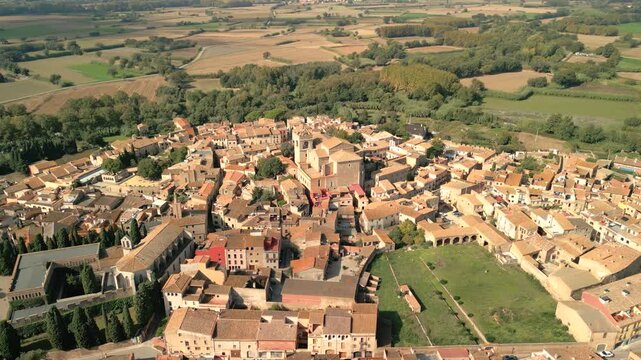 Aerial view of the historic town of Peralada with its stone buildings, narrow streets, and surrounding agricultural fields in Peralada, Catalonia, Spain.