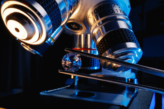 Closeup diamond held with tweezers under microscope for laboratory analysis and gemstone inspection background for jewelry quality control