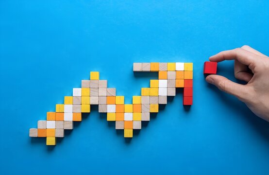 Hand placing red square block at end of upward arrow made of colorful wooden pieces on bright blue background symbolizing growth progress success improvement logical thinking artwork  generated ai