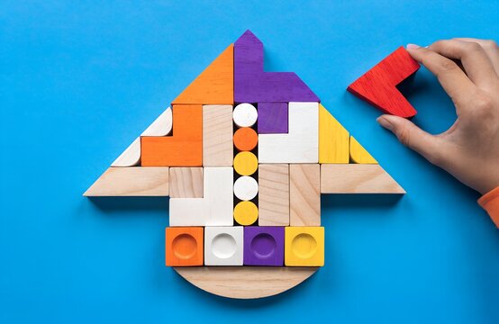 Hand holding red puzzle piece near colorful wooden arrow arrangement of triangles squares rectangles circles on bright blue background symbolizing growth progress logical thinking artwork  generated a