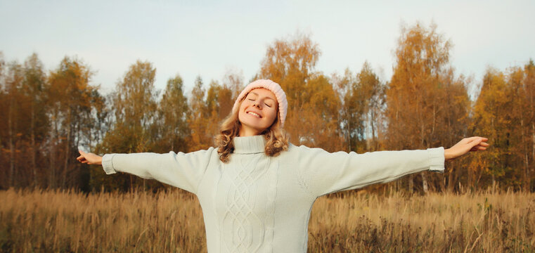 Happy young woman in autumn park, joyful girl enjoying warm weather, nature background
