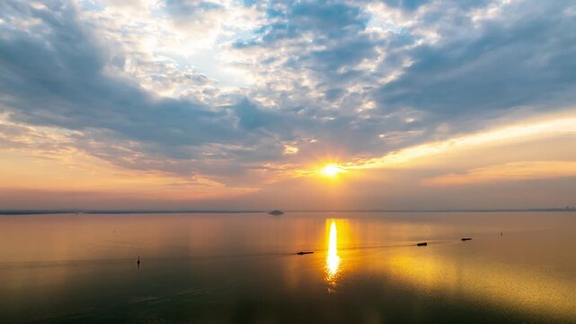 Hefei Chaohu Zhongmiao Sunset Tyndall Light Aerial Timelapse: Golden Rays Pierce Clouds Over Calm Waters with Solitary Boats at Dusk