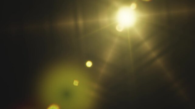 Bright golden lens flare effect glowing against a dark background in video sequence