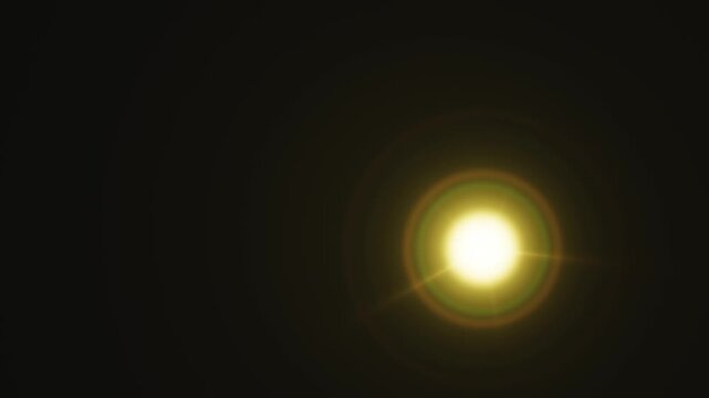 A bright yellow digital lens flare effect gleaming on a dark background.