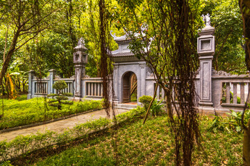 Naklejka premium Traditional stone gate in a green Vietnamese temple garden