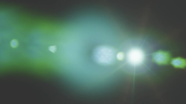 A realistic digital lens flare effect shining bright light across dark background screens