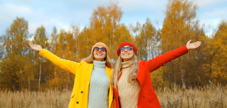 Happy cheerful young two women friends in autumn park, stylish girlfriends smiling together outdoors