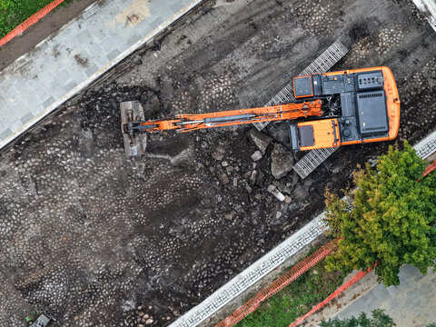 Daytime road construction and asphalt resurfacing with excavator in urban area