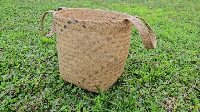 basket of rice,Handwoven basket rests on green grass. Baskets crafted from natural fibers, sturdy and elegant. Handles looped for easy carrying. Earth tones blend with outdoor scenery