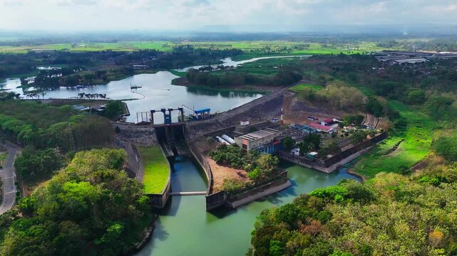 Aerial view of PLTA Sengguruh hydroelectric power plant with its dam, reservoir, and surrounding lush greenery in Malang, East Java, Indonesia.