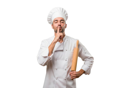 Young male chef wearing a white uniform and hat holding a wooden rolling pin, making a silent gesture with his finger, isolated on transparent background
