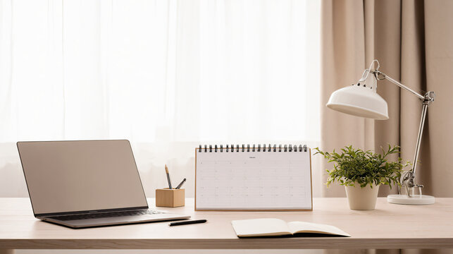 Clean lifestyle photograph of an organized home office desk viewed from a slightly elevated angle, laptop closed, blank notebook, pen holder, desk calendar with completely blank pages