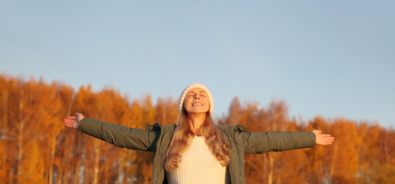 Happy young woman in autumn park, joyful girl enjoying warm sunny weather, nature