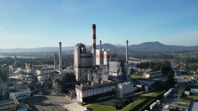 Aerial view of DS Smith Viana Paper Mill with its tall chimney and industrial structures surrounded by green landscape in Deocriste, Viana do Castelo, Portugal.