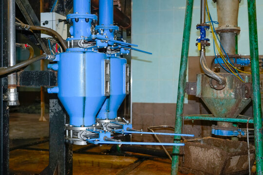 Heavy blue equipment separates and cleans recycled paper pulp materials within a functional production facility during the daily operation cycle