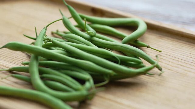 Close up view of vibrant green French beans on a wooden board
