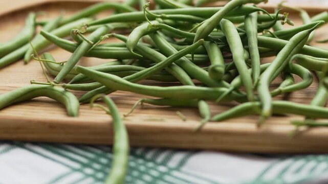 Close-up camera movement over organic raw green beans on a wooden surface
