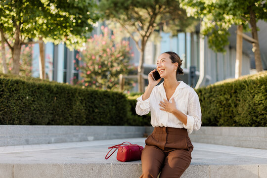 Korean woman chatting on her phone in a sunny park
