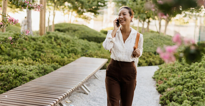 Korean woman enjoying a sunny day while chatting on the phone in a park