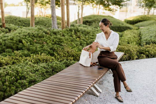 Korean woman enjoys a peaceful moment in a lush urban park setting