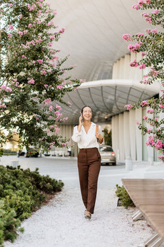 Korean woman walking through a blooming pathway in a modern city
