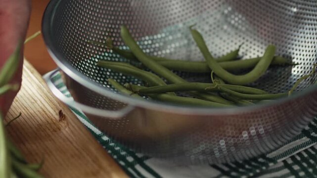 Low angle view of washing organic green beans in a metal colander