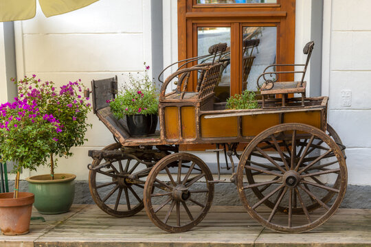 View of an antique wooden carriage used as a decorative planter with blooming flowers on a wooden deck in Hallstatt, Upper Austria, Austria.