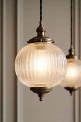 Naklejka premium Glass globe pendant lamp with ribbed texture emits warm light. Brass accents and vintage design add elegance to home interiors. Ideal for luxury spaces.