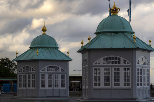 View of the green-domed guard houses at Amalienborg Palace with ornate gold finials and white window frames under a cloudy sky in Copenhagen, Denmark.