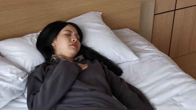 southeast asian sick adult lying down with headache and fever, coughing on bed