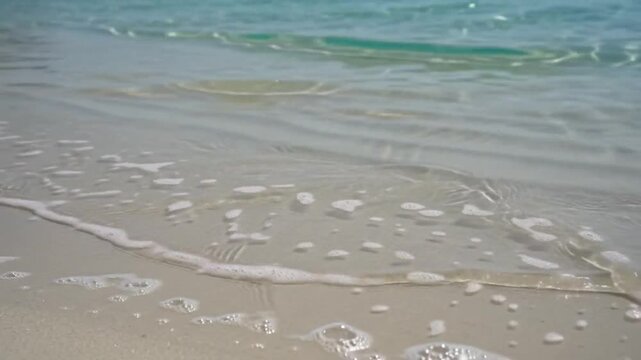 Waves washing over sandy beach shore with waves gently lapping ocean waves ripple water coast video tide foam blue calm sea
