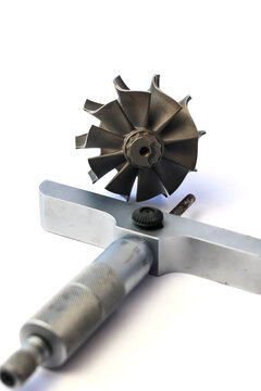 Automotive turbocharger turbine wheel shaft and precision depth micrometer measuring tool on white background.