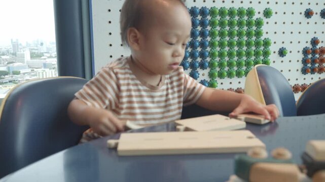 A young child is focused on playing with colorful building blocks at a creative play area, fostering early learning and development through hands-on activity in a bright and inviting environment.