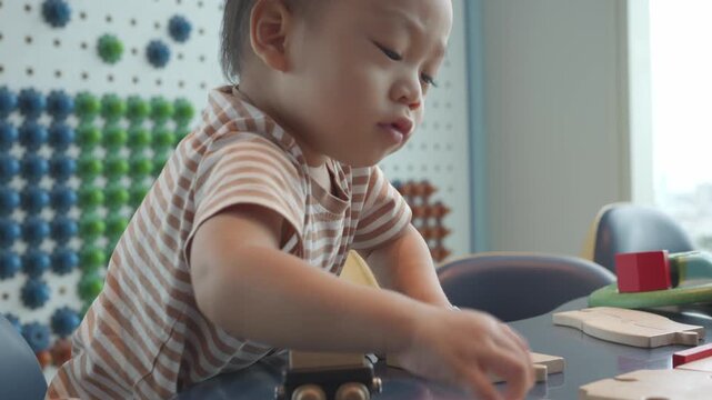 A focused young child plays with colorful wooden toys in an interactive learning environment. The scene captures the essence of early childhood development and creativity, showcasing the joy of explor