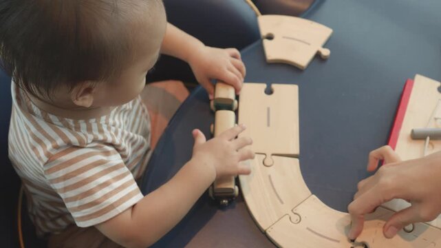 A young child is engaged in building a wooden train track, exploring creativity and fine motor skills through play. The scene captures the joy of childhood and the importance of imaginative toys for d