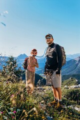 Father helps his daughter drink from a hydration pack on a sunny mountain trail. Hydration and child care on a hike for parenting, outdoor gear and family travel themes © Екатерина Лукашина