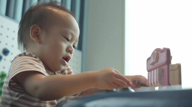 A toddler focuses intently while playing with colorful wooden blocks at a bright, cozy environment. This scene captures the joy of early childhood learning and creative exploration.