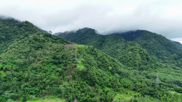 Aerial view of Lio citarik mountains and village with lush green forest and power lines in Kecamatan Pelabuhanratu, Jawa Barat, Indonesia.