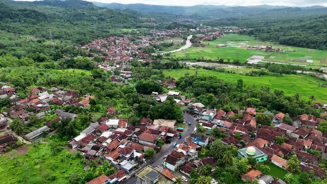 Aerial view of Lio citarik village with lush rice fields and river winding through the landscape in Kecamatan Pelabuhanratu, Jawa Barat, Indonesia.