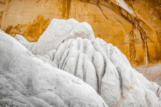 View of the white chalky rock formations of Tuzbair with eroded textures against golden cliffs in the desert landscape of Mangystau District, Mangystau Region, Kazakhstan.