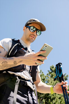 UGC man checking smartphone hiking app on trail in Pyrenees blue sky