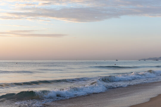 Cam Ranh, Vietnam. Soft pastel sunrise over a tranquil ocean shoreline with gentle waves breaking on the sand, evoking peaceful, serene and contemplative moods of travel, relaxation and nature 