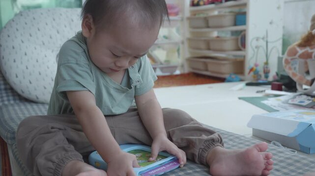 A young child sitting comfortably on a cushion, focused on an educational device. The playful and cozy learning space is bright and inviting, promoting curiosity and exploration through interactive pl