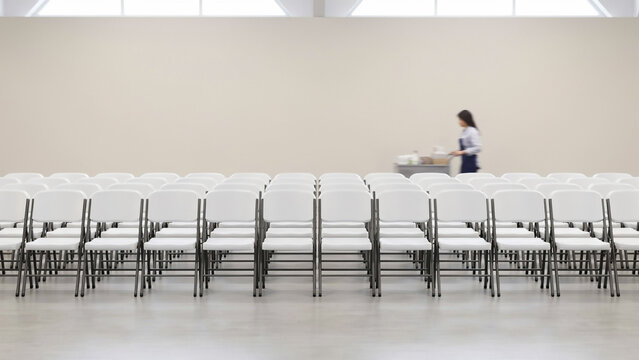 Empty Event Hall with Rows of White Chairs and Maid Preparing Setup