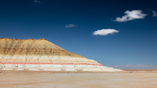 View of the striped sedimentary rock formations of Gora Bokty under a clear blue sky in Karakiya District, Mangystau Region, Kazakhstan.