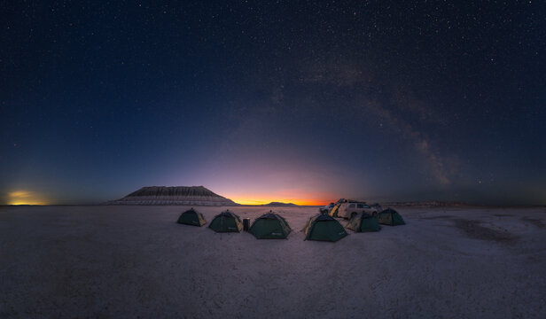 View of Gora Bokty under a starry night sky with camping tents set up on the desert floor in Karakiya District, Mangystau Region, Kazakhstan.